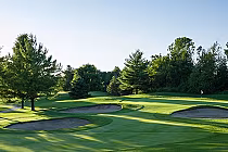 Scenic view of a golf course with green fairways, sand bunkers, and trees, perfect for a memorable golf experience in Ontario.