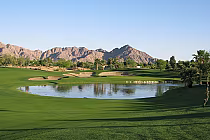 Scenic view of SilverRock golf course in La Quinta with lush green fairways, water hazards, trees, and mountains in the background.