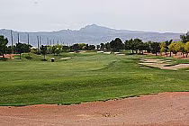 A scenic view of Stallion Mountain Golf Course with lush green fairways, sand bunkers, trees, and mountains in the background.