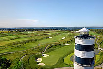 Aerial view of The Nest golf course at Friday Harbour with lush green fairways, sand traps, and a lighthouse-shaped structure.