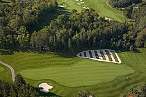 Aerial view of Wooden Sticks Golf Course featuring lush green fairways, a sand bunker, and a unique white gravel area designed by Ron Garl.