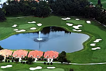 Aerial view of Lake Jovita Golf & Country Club with a pond, fountain, lush green fairways, sand traps, and surrounding trees.