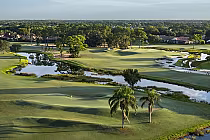 A scenic golf course at PGA National Resort-The Match Course with water hazards, lush green fairways, and trees, designed by Andy Staples.