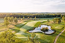 A scenic golf course in Niagara National, Ontario, featuring lush green fairways, a water hazard, and surrounding trees.