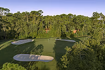 Aerial view of Disney’s Lake Buena Vista Golf Course with sand traps, lush green fairways, surrounded by tall trees and clear blue sky.