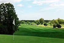 Scenic view of Briar Fox Golf Club in Ontario with lush green fairways, trees, and a flag on the putting green under a partly cloudy sky.