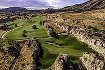 Aerial view of Fossil Trace Golf Club with lush green fairways, rocky cliffs, and scenic mountainous landscape outside Denver.