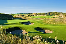 Scenic view of Eagles Nest Golf Club with lush green fairways, sand bunkers, and rolling hills under a clear blue sky.