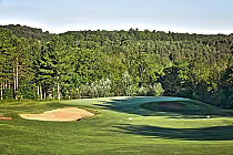 Golf course with sand traps, green fairways, surrounded by lush trees at Mill Run Golf Club, featuring championship and Highland courses.