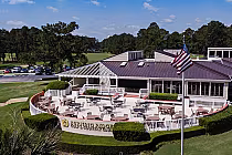 Outdoor view of Burning Ridge Golf & Country Club with a patio, American flag, and lush green landscape in Myrtle Beach.
