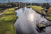 Aerial view of Crow Creek Golf Club with lush green fairways, water hazards, trees, and a boat dock on a sunny day.