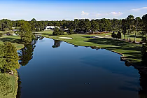 A scenic golf course with water hazards, sand bunkers, lush green fairways, and tall trees, part of Myrtle Beach National's West Course.