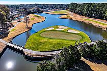 Aerial view of River Club golf course with lush green fairways, water hazards, and surrounding trees under a clear blue sky.