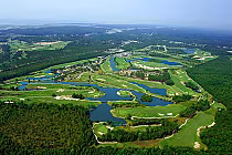 Aerial view of Thistle Golf Club's lush, green golf course with water hazards, sand traps, and surrounding trees.