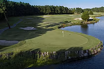 A scenic golf course with a green, sand bunkers, water hazard, surrounded by trees, with a "Legends Moorland - COMING SOON" sign.