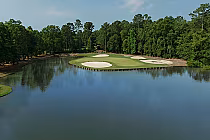 A scenic view of Arrowhead Country Club's 27-hole golf course with sand traps, lush green fairways, and a surrounding water hazard.