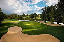 Scenic golf course at Inverness Club with sand traps, lush green fairways, trees, water hazards, under a partly cloudy sky.