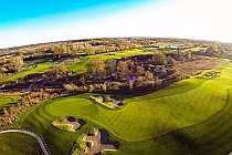 Aerial view of FireRock Golf Club with lush green fairways, sand traps, trees, and natural landscape features.