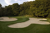 Scenic golf course at Horseshoe Resort with sand bunkers, lush green grass, and tall trees in the background.