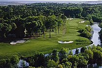 Aerial view of Sea Trail-Maples golf course with lush green fairways, sand bunkers, surrounded by tall oaks, pines, and water hazards.