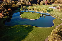 Aerial view of Innerkip Highlands golf course featuring a small island green surrounded by water, lush fairways, and trees.