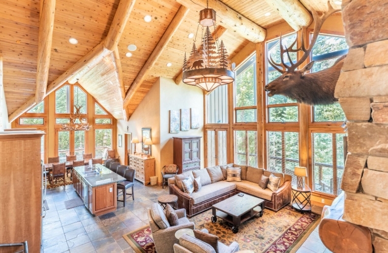 Luxurious Keystone Ultra Premium Condo interior with high vaulted ceilings, large windows, and rustic decor, including a mounted elk head.