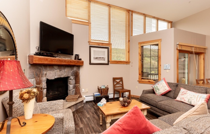 Cozy living room in a Keystone Premium Condo with a stone fireplace, wooden accents, and comfortable seating.