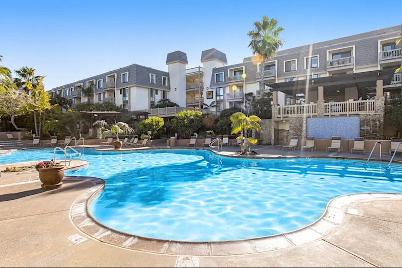 Luxury 1-bedroom condo at North Coast Village in Oceanside, CA, with pool, hot tub, gym, and ocean views in the background.