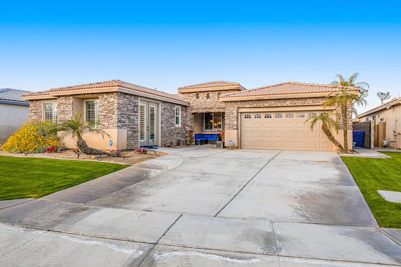 Indio Diamond - Indio, CA Luxury vacation home in Indio, CA with stone exterior, a two-car garage, palm trees, and a well-maintained lawn.