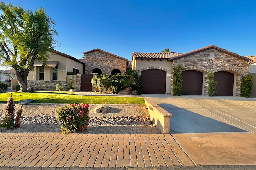 Carefree Living - Indio, CA Luxury 5-bedroom home in Indio, CA with a landscaped yard, stone accents, and three garage doors, perfect for golf vacations.