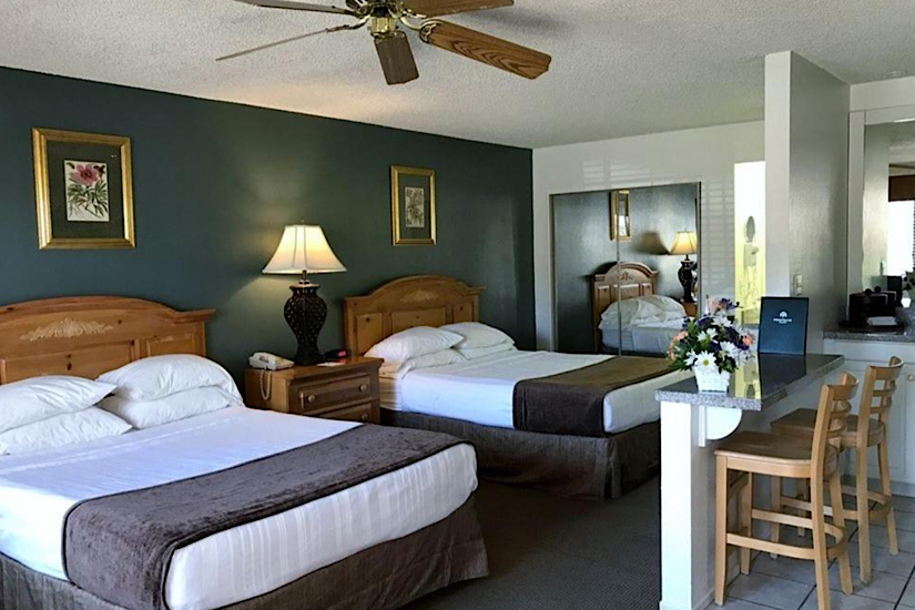 INDIAN PALMS COUNTRY CLUB & RESORT Interior of a hotel room at Indian Palms Country Club & Resort with two beds, wooden furniture, lamps, and a small kitchen area.