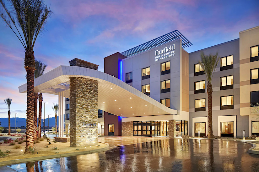 Fairfield by Marriott Inn & Suites Indio Coachella Valley Exterior view of Fairfield by Marriott Inn & Suites in Indio Coachella Valley at dusk, with palm trees and a lit-up entrance.