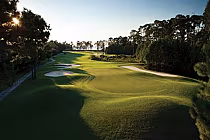 A scenic golf course with lush green fairways, sand bunkers, and tall trees, under a clear sky at Peninsula Golf & Racquet Club, Alabama.