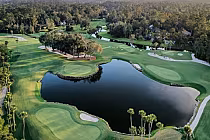 Aerial view of The Yards golf course with lush green fairways, water hazards, trees, and a surrounding wooded area in North Florida.