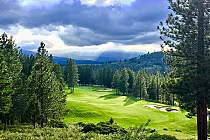 Scenic view of Nakoma Golf Resort's Dragon Course with lush green fairways, surrounded by tall pine trees and mountain backdrop.