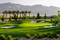 Scenic view of Aliante Golf Club in North Las Vegas with lush green fairways, sand bunkers, palm trees, and mountains in the background.