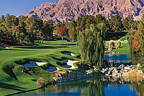 Scenic view of Shadow Creek Golf Course with lush green fairways, water features, trees, and mountains in the background.