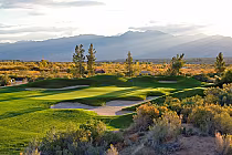 Scenic view of Casablanca Golf Club in Mesquite with lush green fairways, sand bunkers, and mountain backdrop at sunset.