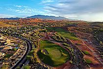 Aerial view of Coral Canyon Golf Course in St. George, Utah, with lush green fairways, surrounding residential area, and scenic desert mountains.