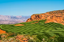 Sand Hollow Resort's Links Course in Utah features lush green fairways, sand bunkers, and red rock formations under a clear blue sky.