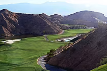 Scenic view of Falcon Ridge Golf Course in Mesquite, Nevada, featuring lush green fairways, rugged mountains, and a water hazard.