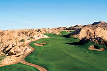 Scenic view of Oasis Golf Club's Canyons Course in Mesquite, featuring lush green fairways amid desert landscape and rugged hills.