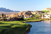 Scenic view of Oasis Golf Club's Palmer Course in Mesquite, featuring lush green fairways, water hazards, and desert mountains.
