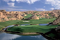 Scenic view of Wolf Creek Golf Club in Mesquite, Nevada, featuring lush green fairways, water hazards, and rugged desert mountains.