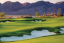 Scenic view of Coyote Springs Golf Club in Las Vegas with lush green fairways, sand bunkers, and desert mountains in the background.