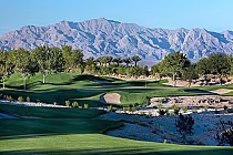 Scenic view of TPC Las Vegas golf course with lush green fairways, trees, and mountains in the background.