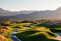Scenic view of Paiute Golf Resort's Sun Mountain course with lush green fairways, sand traps, and mountain backdrop at sunset.