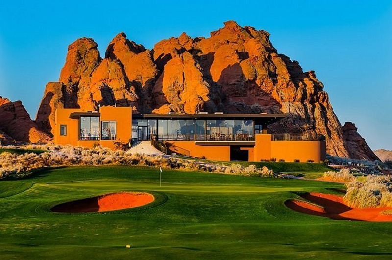 Luxury golf course at Sand Hollow Resort in Utah with a modern building, green fairways, and striking red rock formations.