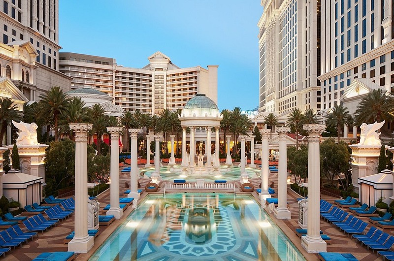 Caesars Palace Luxurious outdoor pool area at Caesars Palace in Las Vegas, featuring classical columns, palm trees, and elegant architecture.