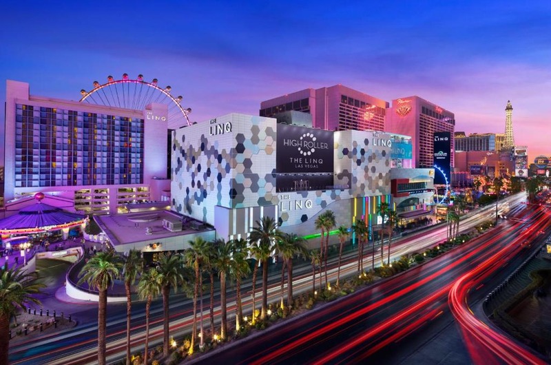 Night view of The LINQ Hotel + Experience in Las Vegas with colorful lights, a Ferris wheel, and busy traffic on the street.